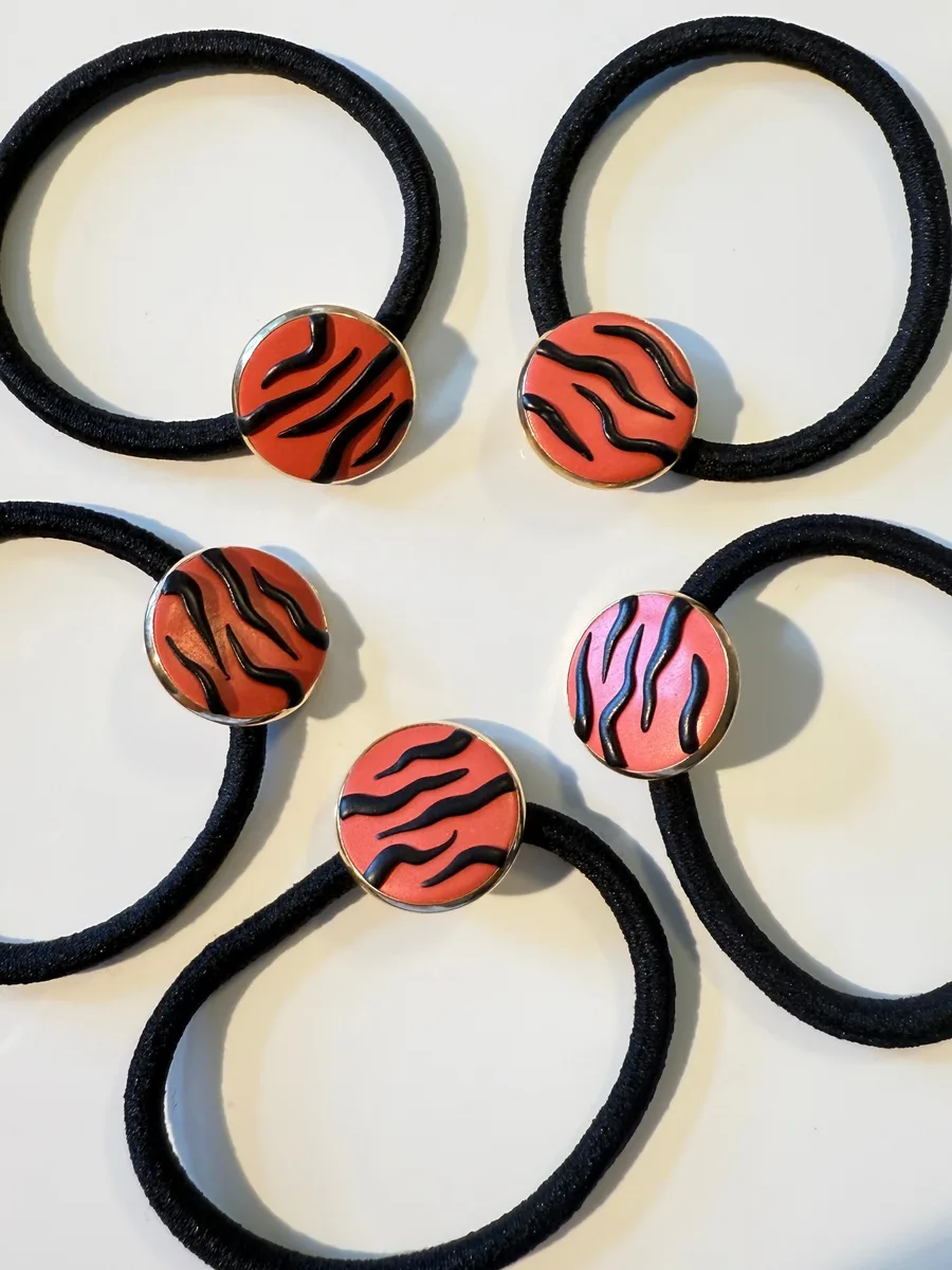 Tiger-stripe clay charms on black hair ties