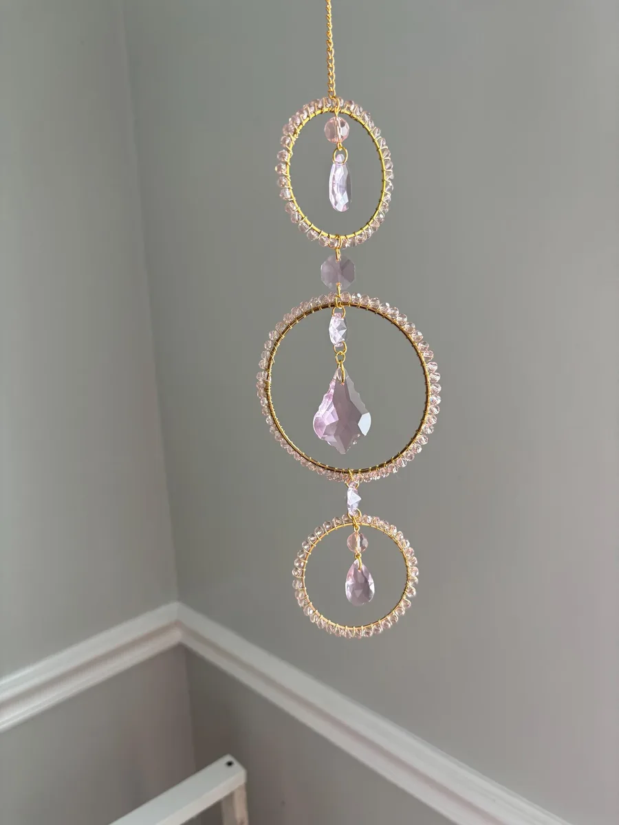 A blush-beaded gold hoop suncatcher throwing rainbows