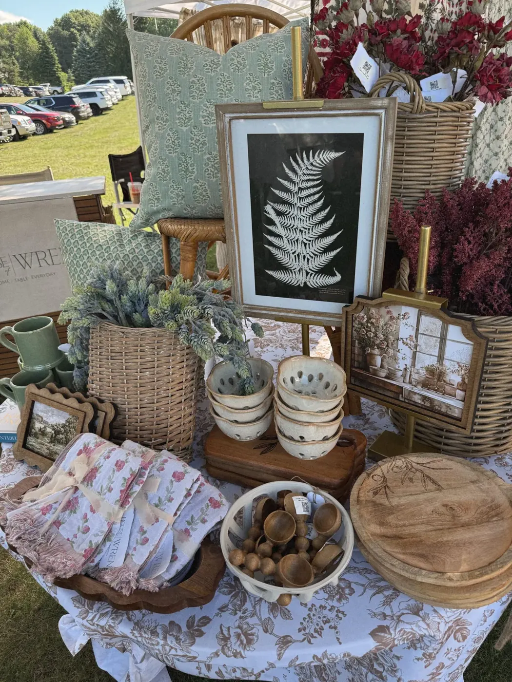 Pillows, framed fern print, baskets and table linens on the House of Wren market table
