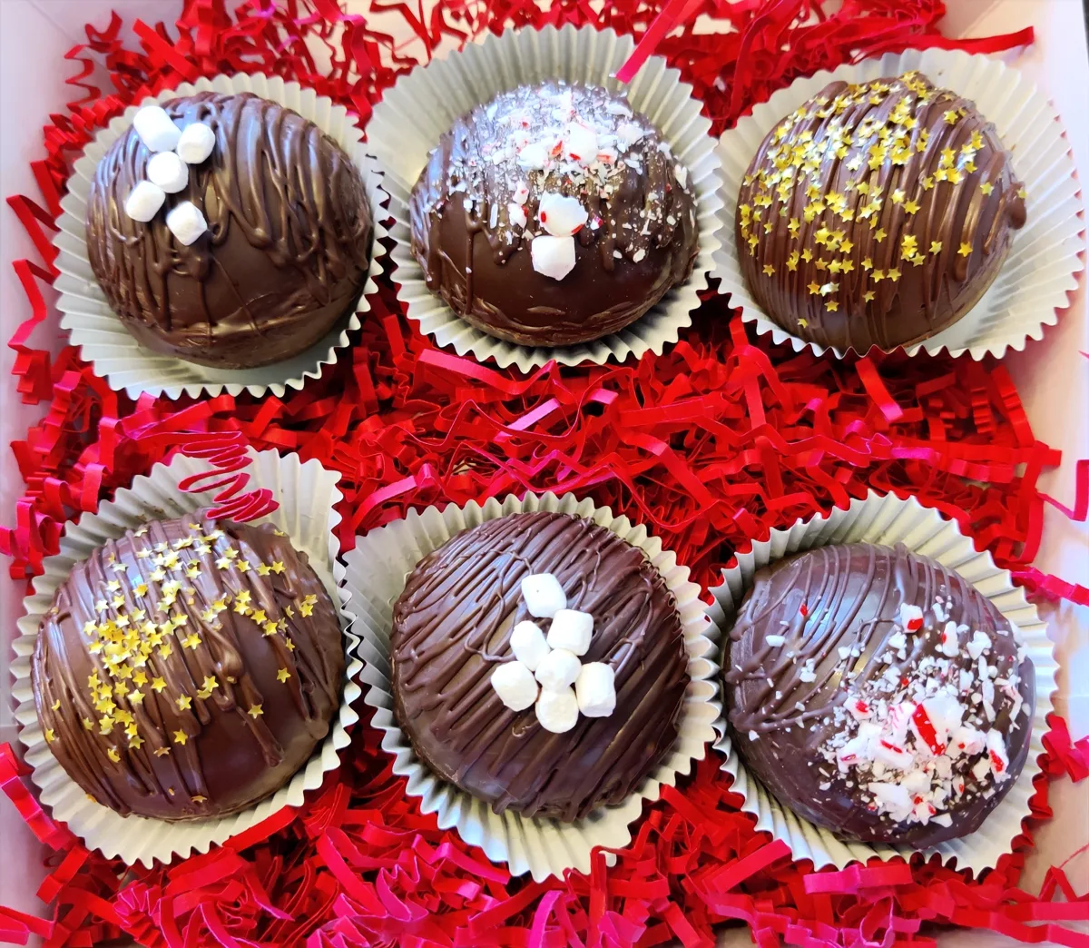Chocolate cocoa bombs topped with marshmallows and sprinkles