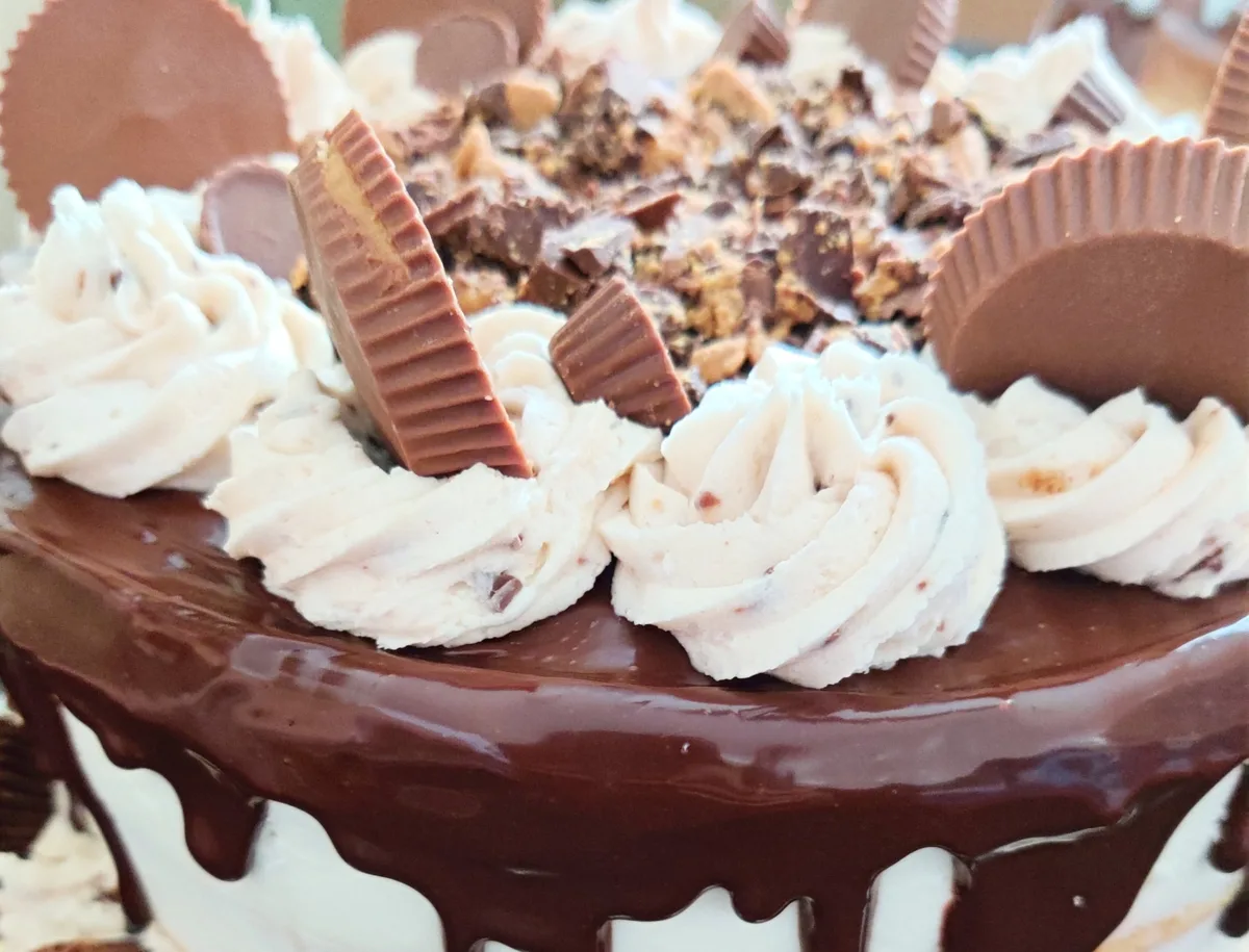 A chocolate drip cake topped with buttercream and peanut butter cups