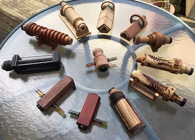A dozen wooden kaleidoscopes laid out in a circle on a glass table