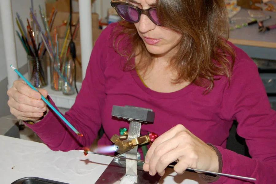 Lisa Inglert shaping a glass bead at the torch