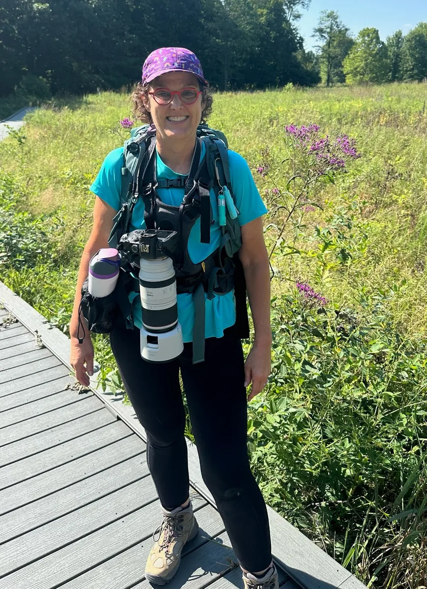 Michelle out on a boardwalk trail with her camera and telephoto lens