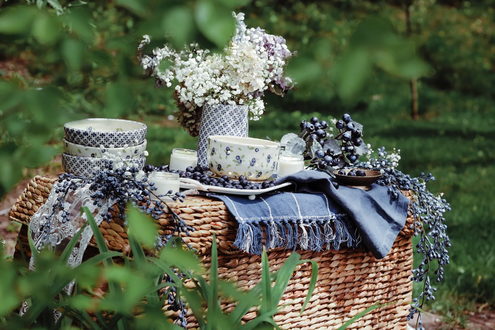 Blue-and-white hand-decorated pottery on a picnic basket outdoors