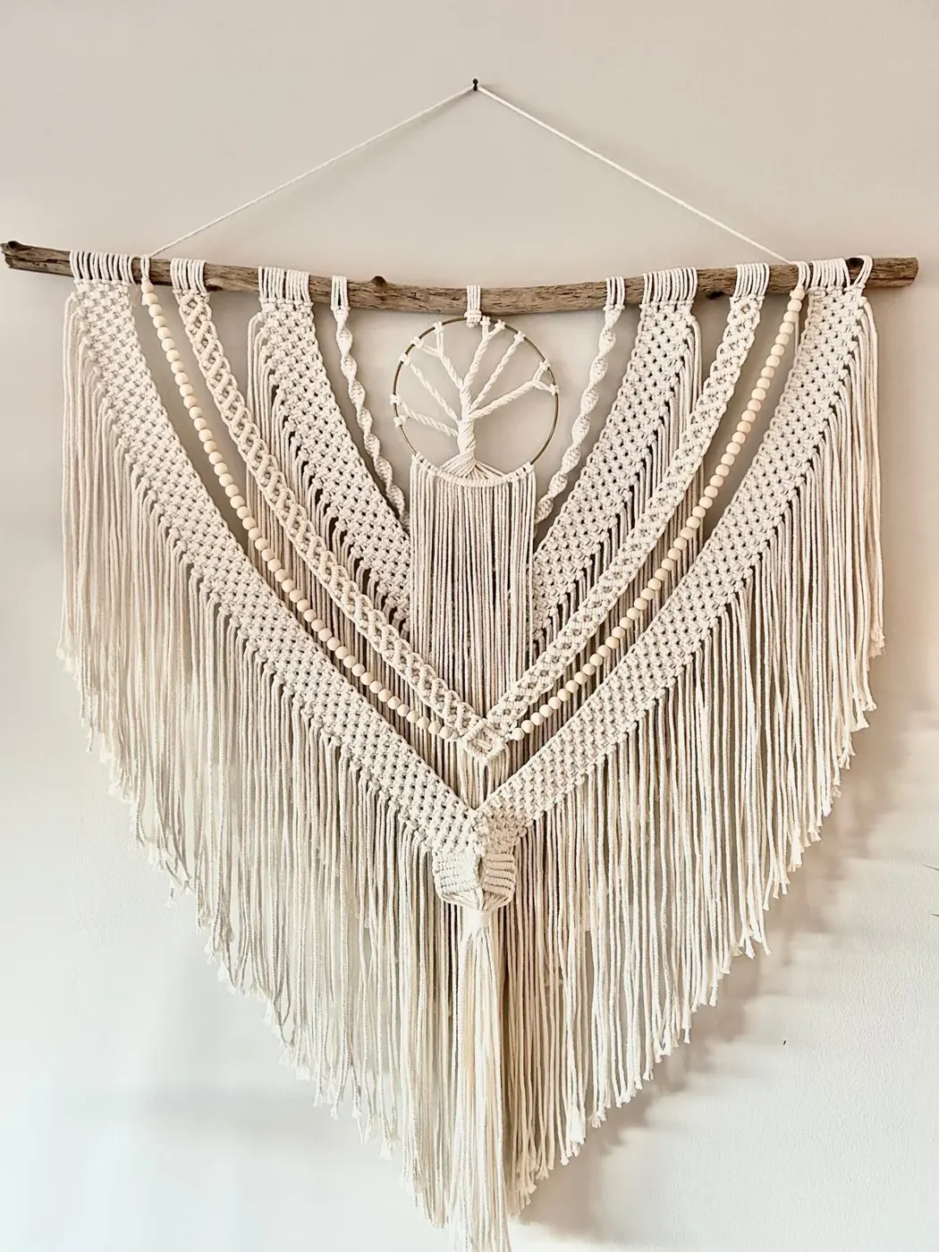 A large macrame Tree of Life wall hanging on driftwood