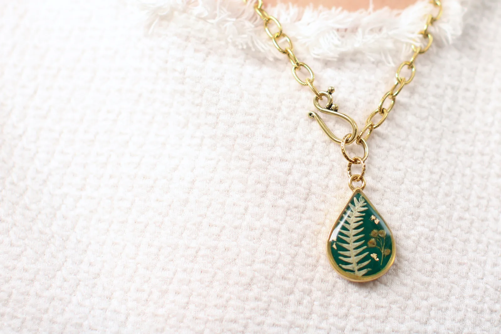 Dark green teardrop earrings with real flowers, worn