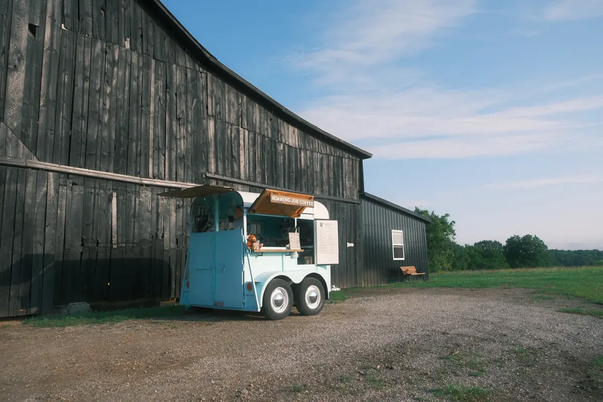 The Roaming Joe Coffee trailer, a restored 1969 horse trailer, serving beside a black barn