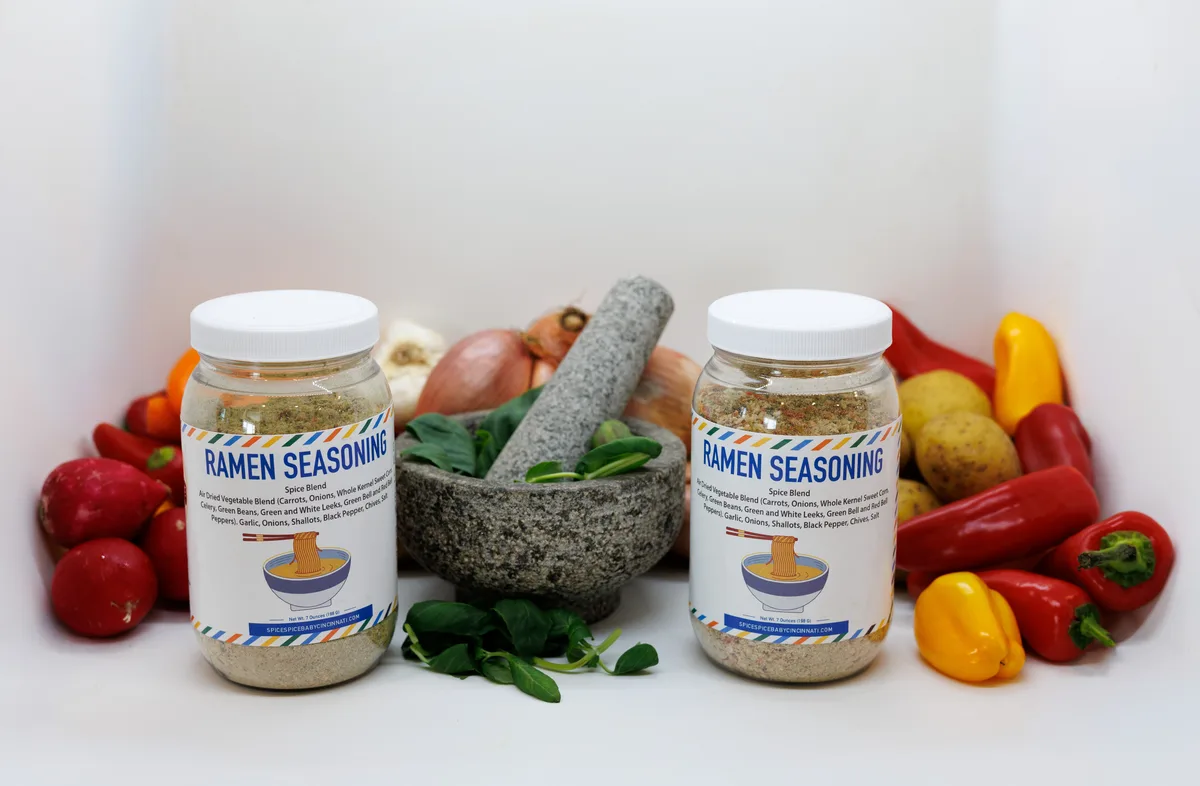 Jars of ramen seasoning with fresh peppers and a mortar and pestle