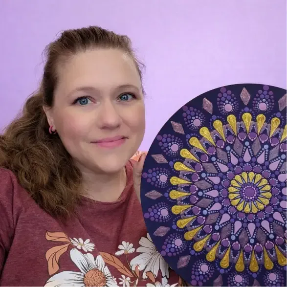 Tara Lynn Pugh holding a purple and gold dot mandala