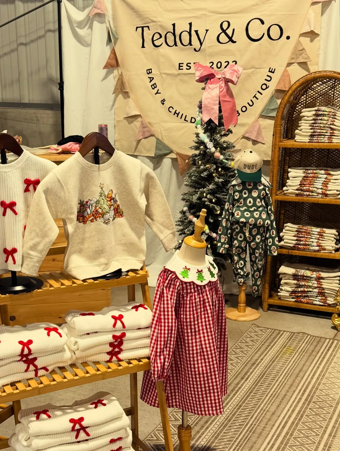 Teddy & Co booth with its baby and children's boutique banner, sweatshirts and dresses