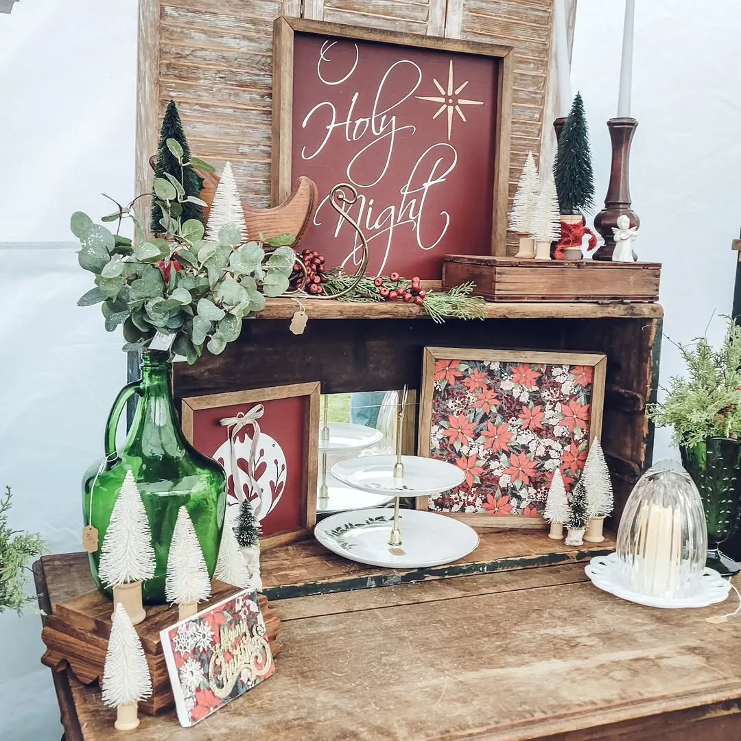 The Blue Goose Decor at Charm: a "Holy Night" sign, poinsettia prints and bottle-brush trees on a vintage hutch