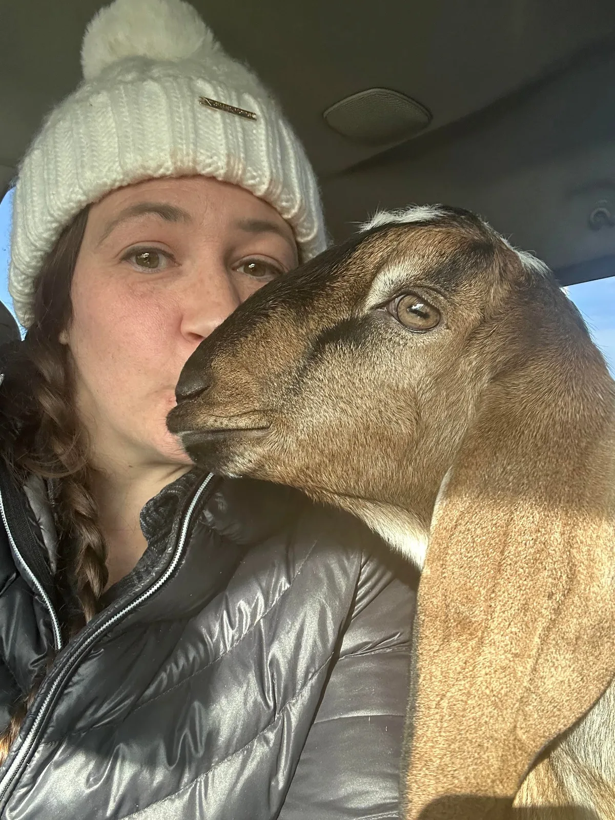 Brooke Taylor in a knit hat with one of her goats