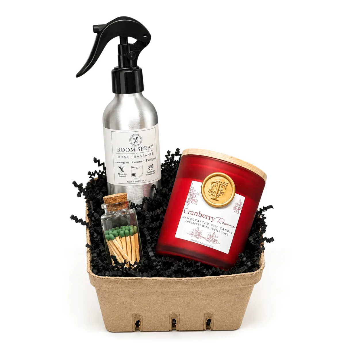 A housewarming gift basket: room spray, a Cranberry Reserve candle and matches in a paper tray