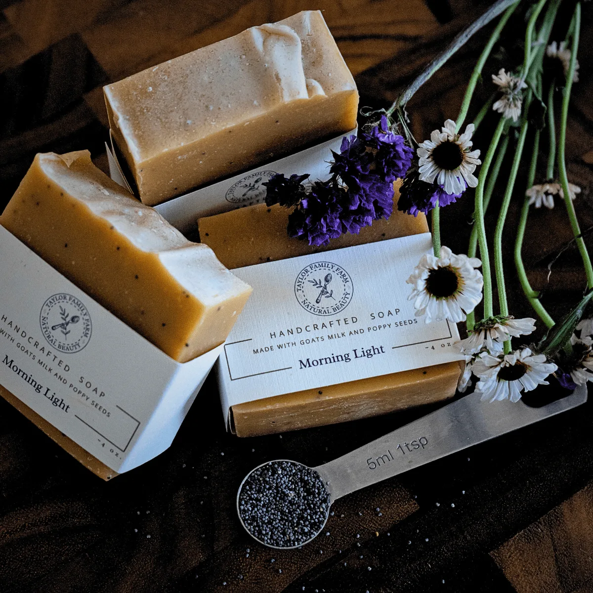 Handcrafted goat's milk soap bars stacked with dried flowers and a scoop of lavender