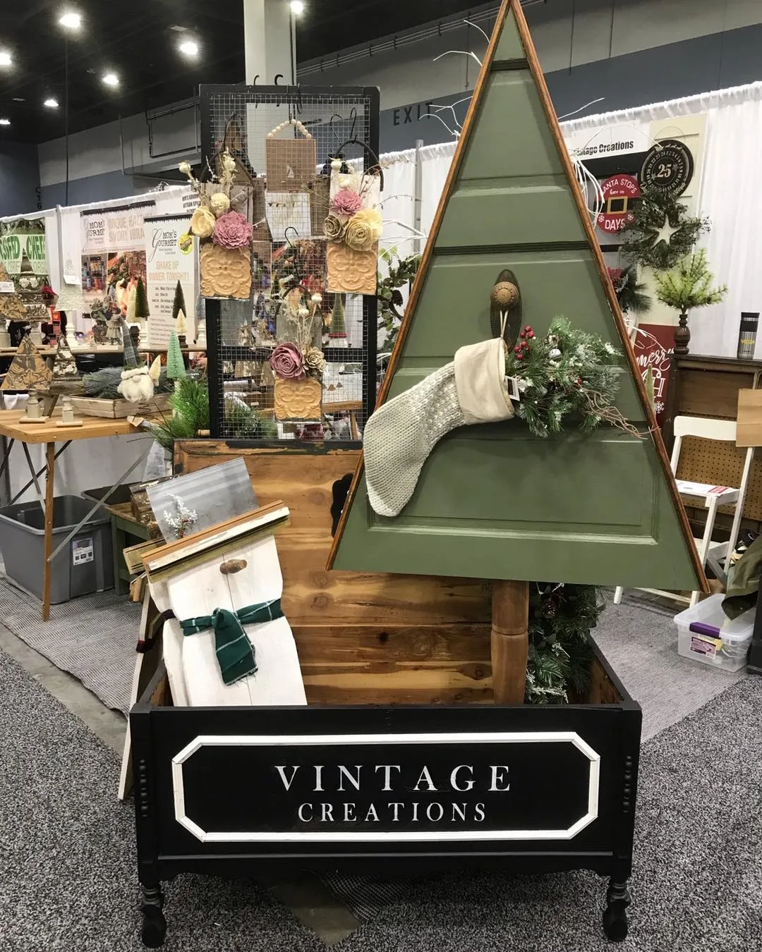 A green wooden Christmas tree with a stocking and greenery